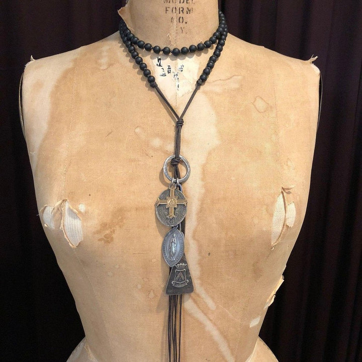 Long layered necklace with black beads and antique-style medallions.
