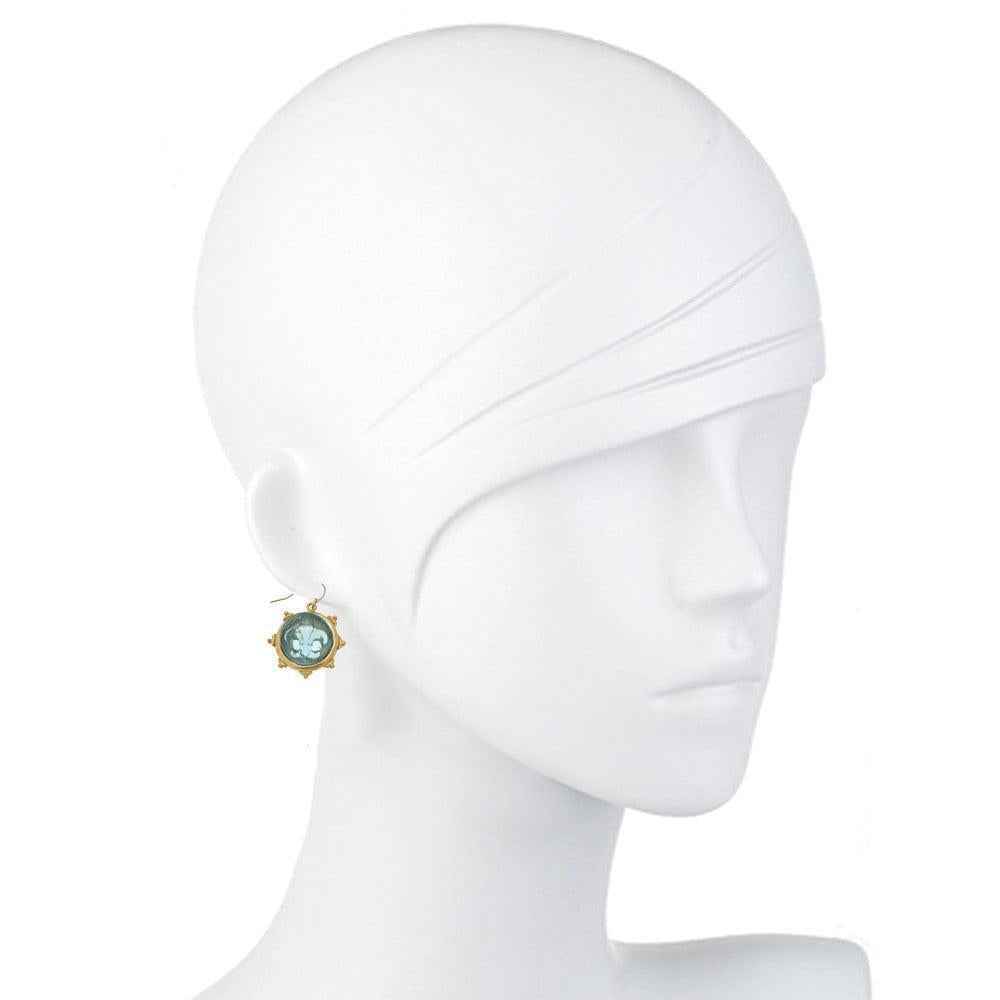 Aqua glass fleur-de-lis earrings on a mannequin.
