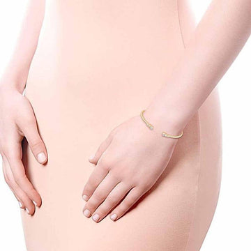 Gold cuff bracelet with small diamonds, on a wrist.
