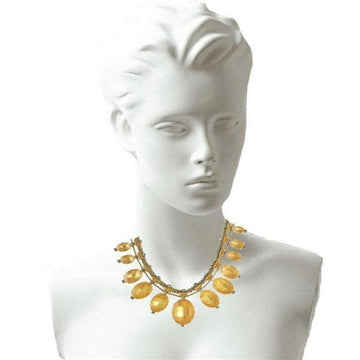 Gold statement necklace with amber oval beads, displayed on a mannequin.
