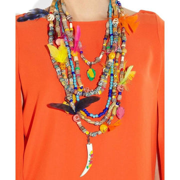 Multi-strand beaded necklace featuring colorful beads, skull accents, feathers, and a unique bone pendant, displayed against a vibrant orange background.

