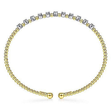 Gold beaded cuff bracelet adorned with a row of shimmering diamonds.
