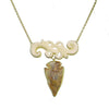 Carved Flur Amber Arrowhead necklace: gold chain, carved bone accents, and a unique amber arrowhead pendant.
