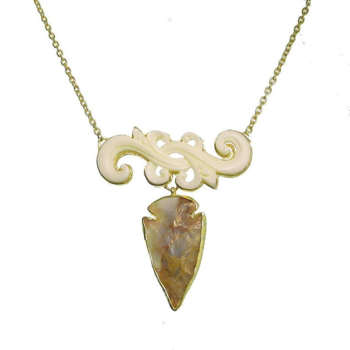 Carved Flur Amber Arrowhead necklace: gold chain, carved bone accents, and a unique amber arrowhead pendant.

