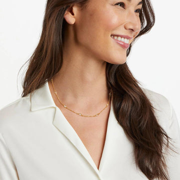 Gold chain necklace with clear stones, worn by a model.

