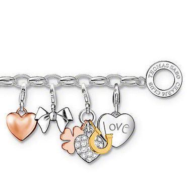 Silver charm bracelet featuring heart, bow, clover, horseshoe, and "love" charms.
