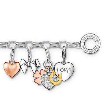 Silver charm bracelet featuring heart, bow, clover, horseshoe, and "love" charms.
