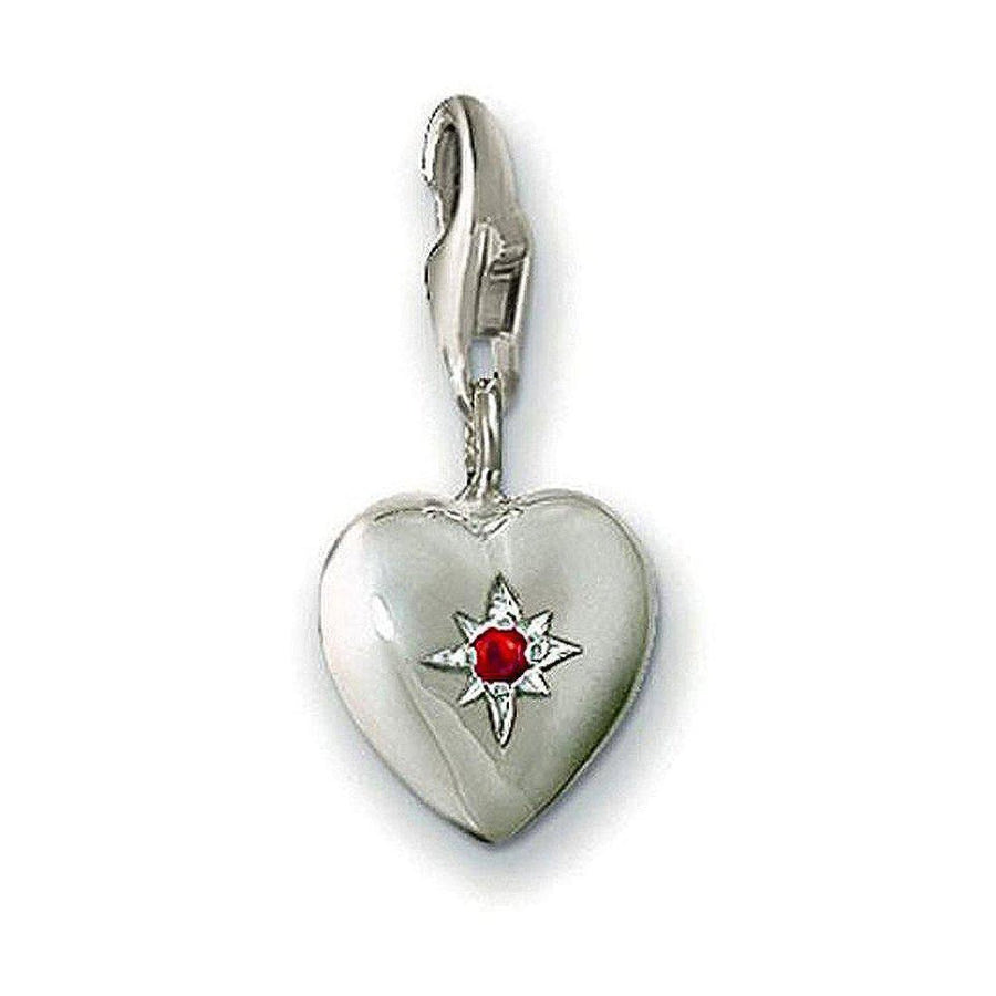 Silver heart charm with red crystal, featuring a starburst design.
