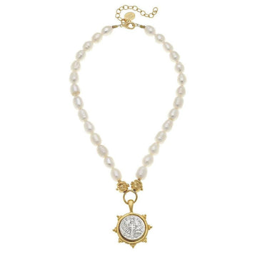 Elegant pearl necklace with a gold coin pendant featuring a cross design.
