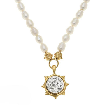 White pearl necklace with antique coin cross pendant in gold setting.
