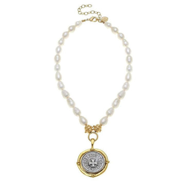 Elegant pearl necklace with spinning coin pendant featuring a cross detail.
