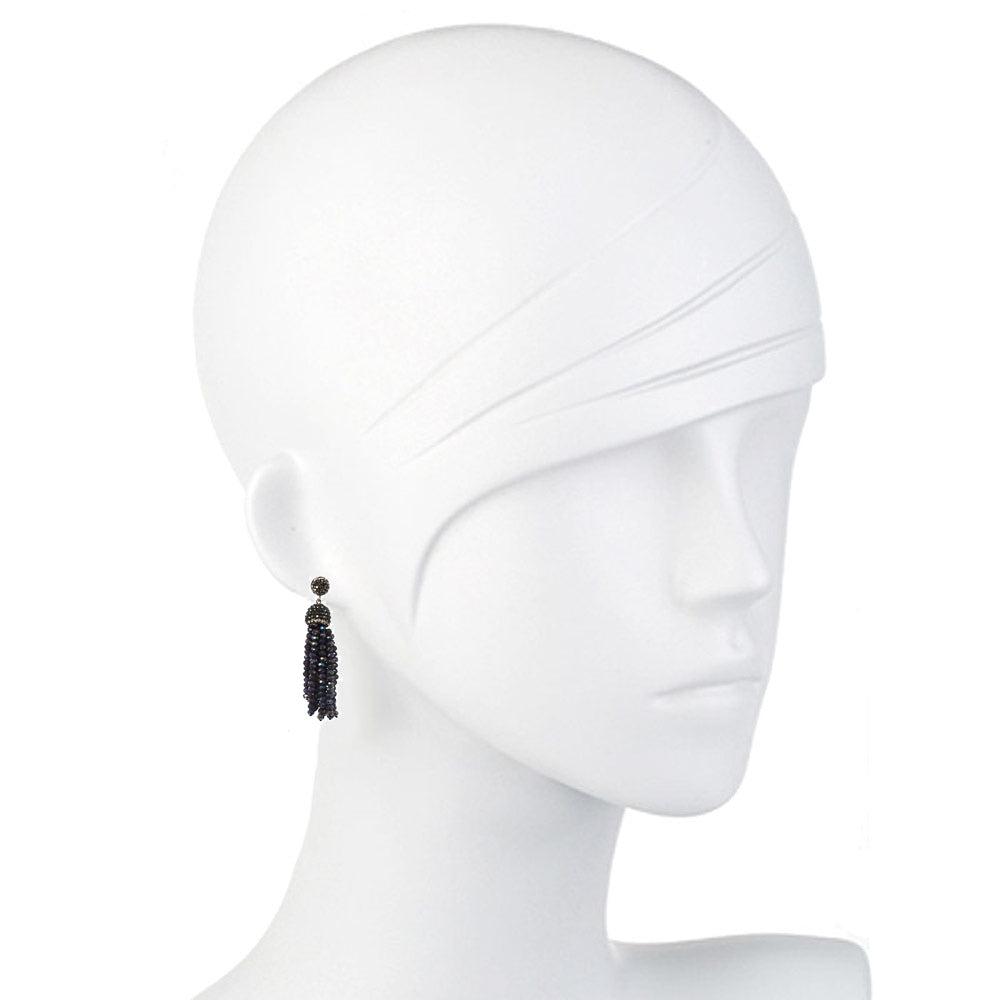 Dark crystal tassel earrings on a white mannequin.
