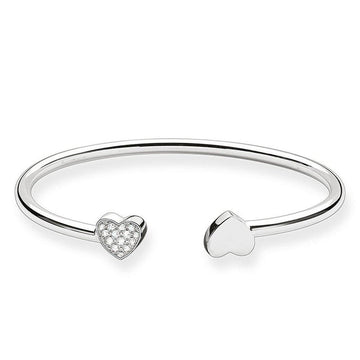 Silver cuff bracelet featuring two heart charms; one embellished with cubic zirconia.
