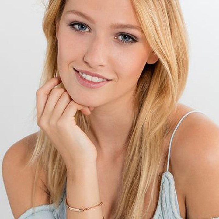Rose gold engraved ID bracelet on a model's wrist.
