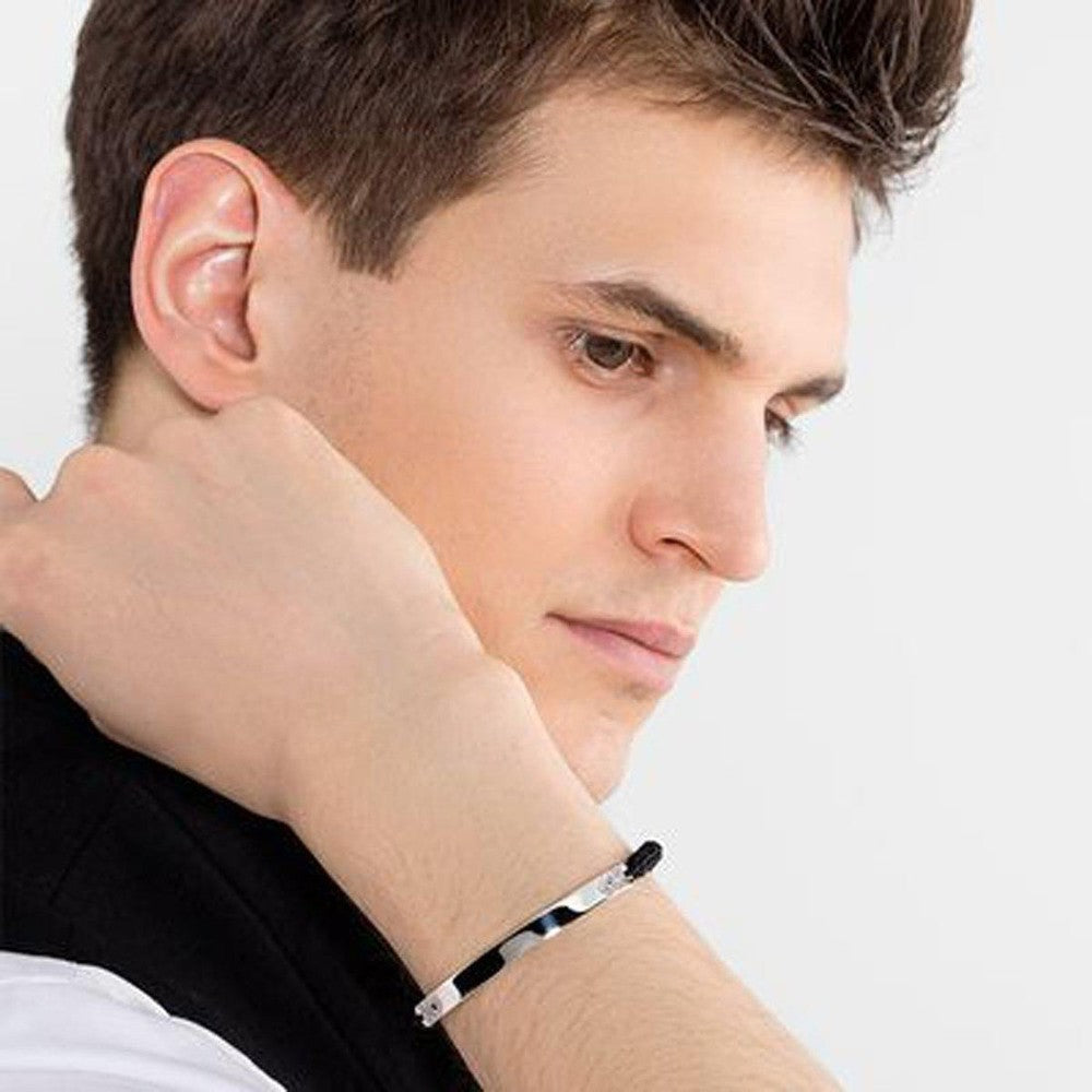 Man's wrist showcasing a silver macrame bracelet with a dark accent.
