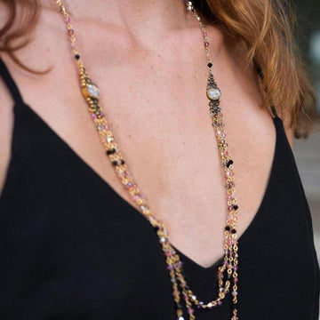 Multi-strand necklace featuring pink and black crystals, gold accents, and detailed pendants.
