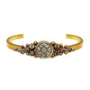Fay Winged Cuff: Gold cuff bracelet featuring a central antique coin with a starburst design, accented with sparkling crystals.
