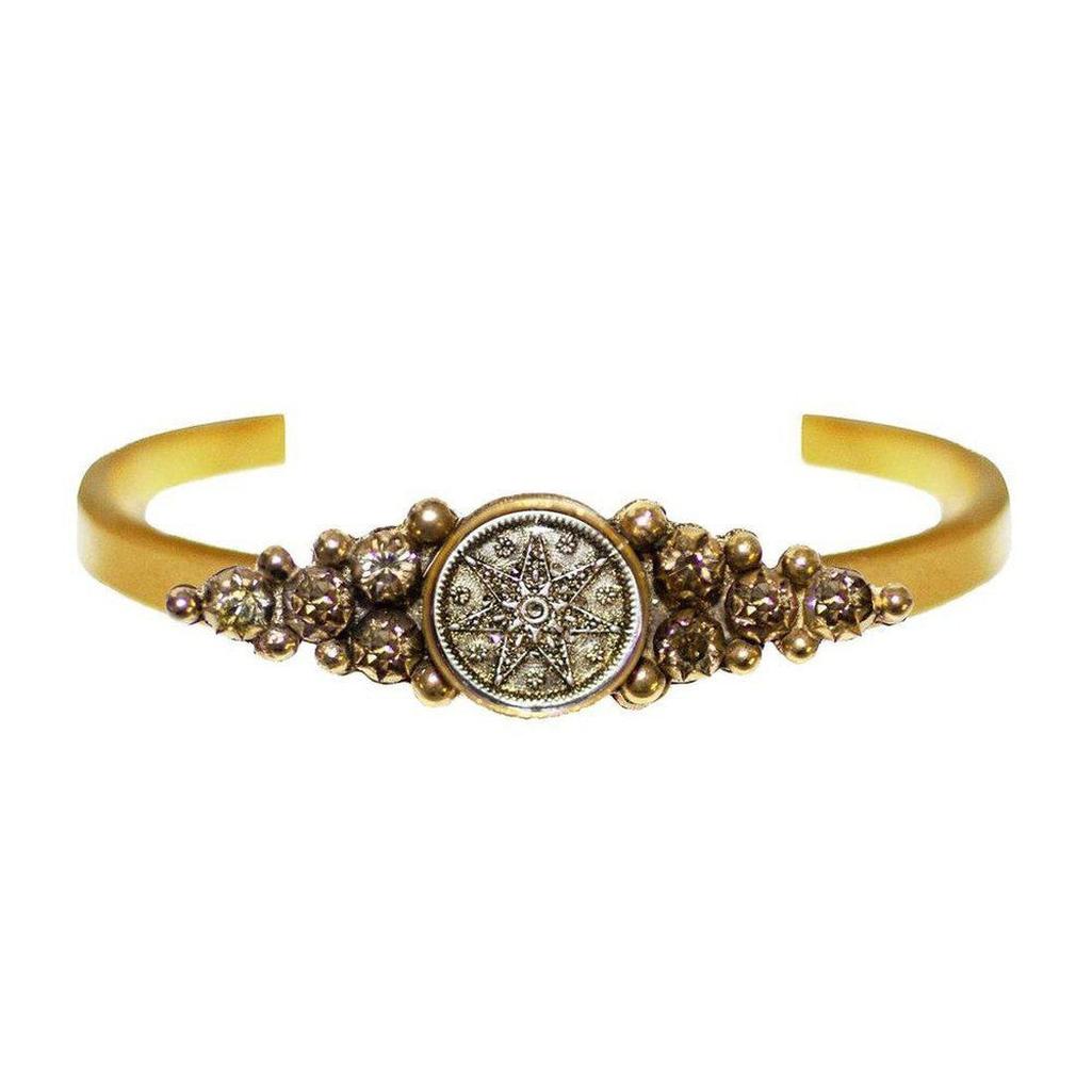 Fay Winged Cuff: Gold cuff bracelet featuring a central antique coin with a starburst design, accented with sparkling crystals.
