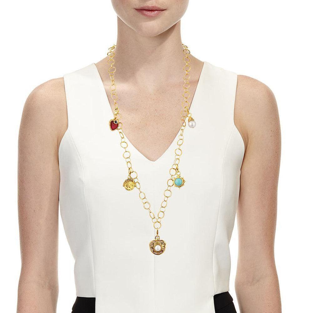 Gold multi-charm necklace featuring colored stones and a pearl, on a model.
