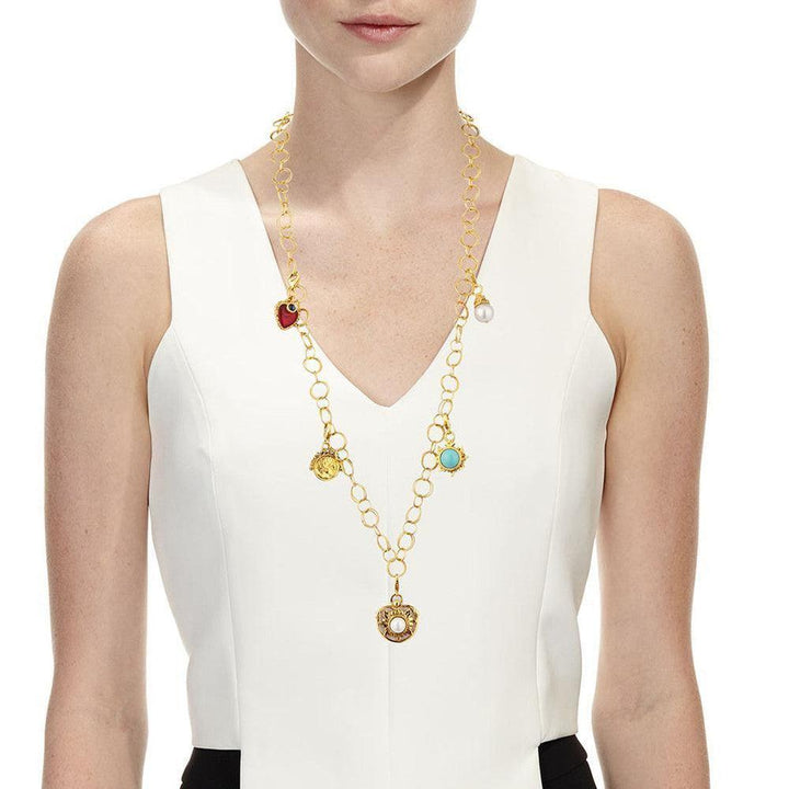 Gold multi-charm necklace featuring colored stones and a pearl, on a model.
