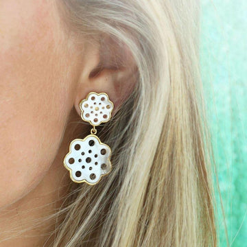 White and gold double-flower drop earrings, detailed pierced design.
