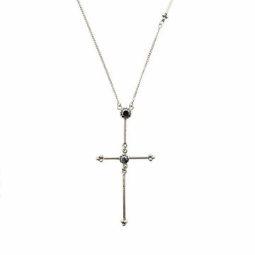Silver cross necklace with dark gemstones, delicate chain.
