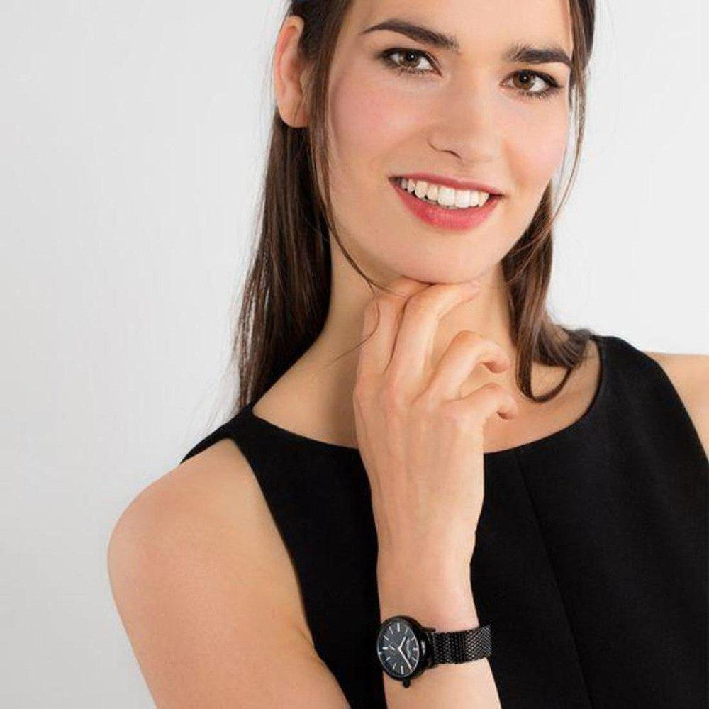 Woman's wrist showcasing a black watch with a mesh band.
