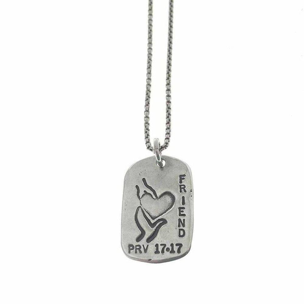 Silver dog tag necklace featuring a heart held in hands, inscribed "FRIEND" and "PRV 17:17".
