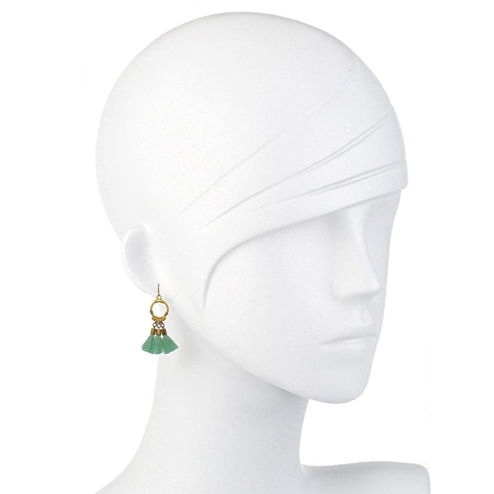 Sage green tassel earrings with gold accents, shown on a mannequin.
