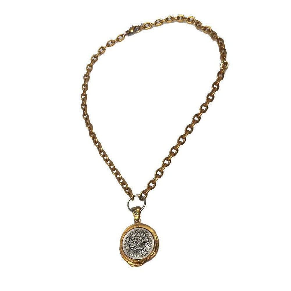 Gold chain necklace with a circular tree of life pendant.
