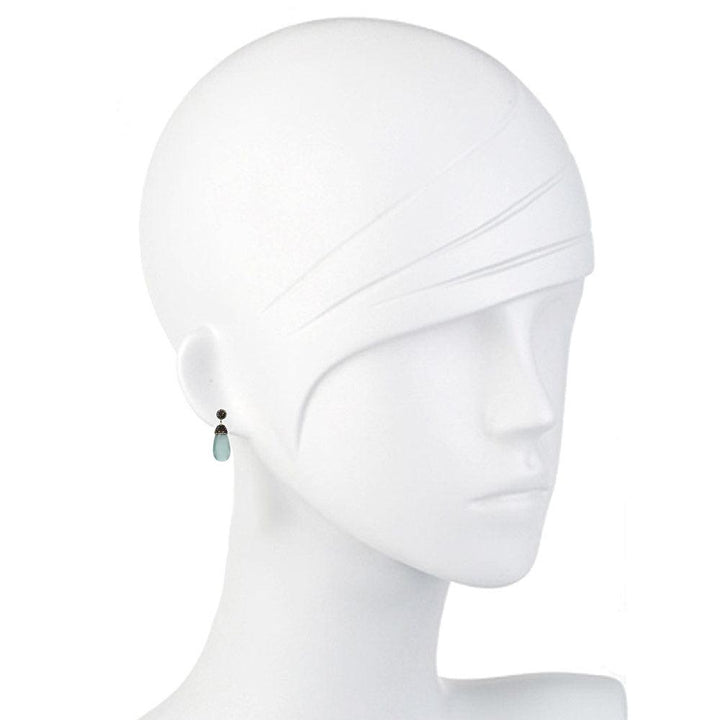 Teardrop gemstone earrings on a mannequin, showcasing light blue and dark gray stones.
