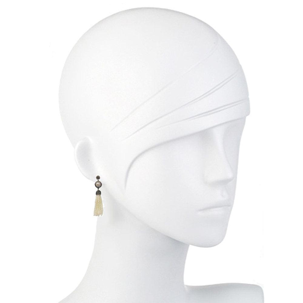 Elegant cream pearl and hematite tassel earrings on a mannequin.
