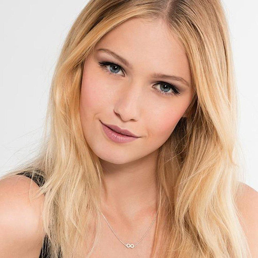 Delicate infinity necklace with sparkling accents, worn by a model with long blonde hair.
