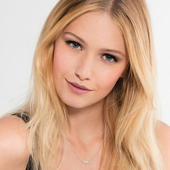 Delicate infinity necklace with sparkling accents, worn by a model with long blonde hair.
