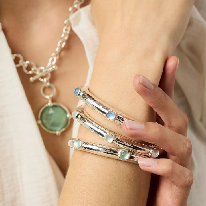 Silver hinged Catalina bangle with a hammered texture and clear cubic zirconia accents worn on a wrist.