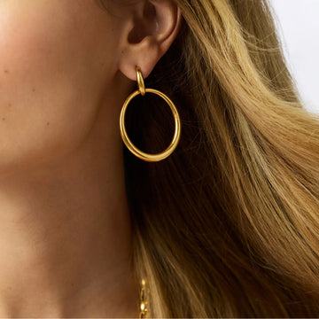Laguna doorknocker earring in 24K gold plate, featuring a polished circular hoop design on a pierced ear.
