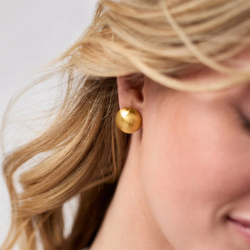 Modern hammered Solara stud earrings in gold plate worn on a pierced ear.