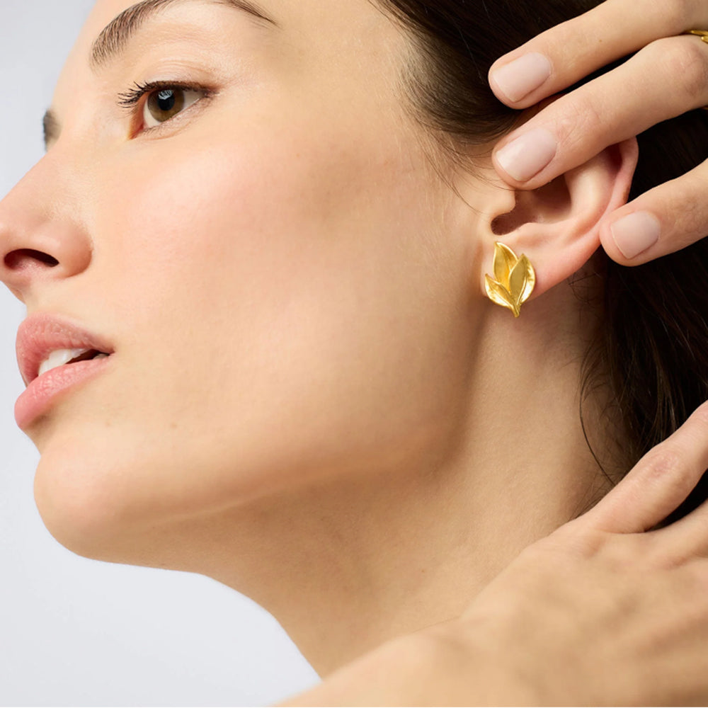 Model wearing a 24K gold-plated triangular Willow stud earring with a faceted crystal center.