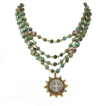 Three-strand turquoise bead necklace with gold accents and a detailed medallion pendant.
