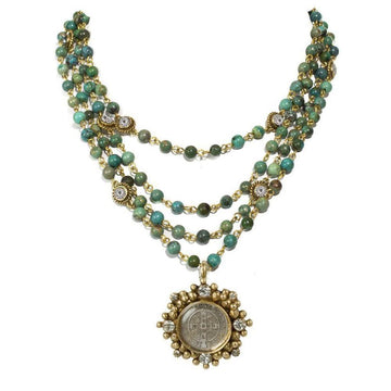 Layered turquoise bead necklace with gold accents and a detailed medallion pendant.
