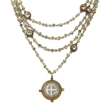 Layered gold necklace with iridescent beads and a detailed medallion pendant.
