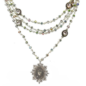 Layered silver necklace with iridescent crystal beads and ornate pendant featuring a sacred heart charm.
