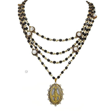 Multi-strand black beaded necklace with gold accents and a Virgin Mary pendant.
