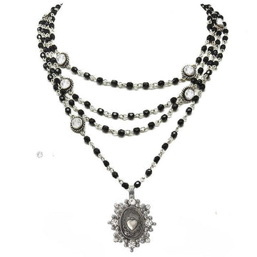 Layered black beaded necklace with silver chain accents and a clear rhinestone heart pendant.
