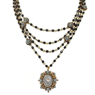 Layered black bead necklace with gold accents and a heart pendant.
