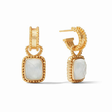 Gold hoop earrings with a dangling white gemstone, detailed close-up.
