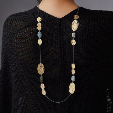 Long gold and labradorite stone necklace on a black sweater.
