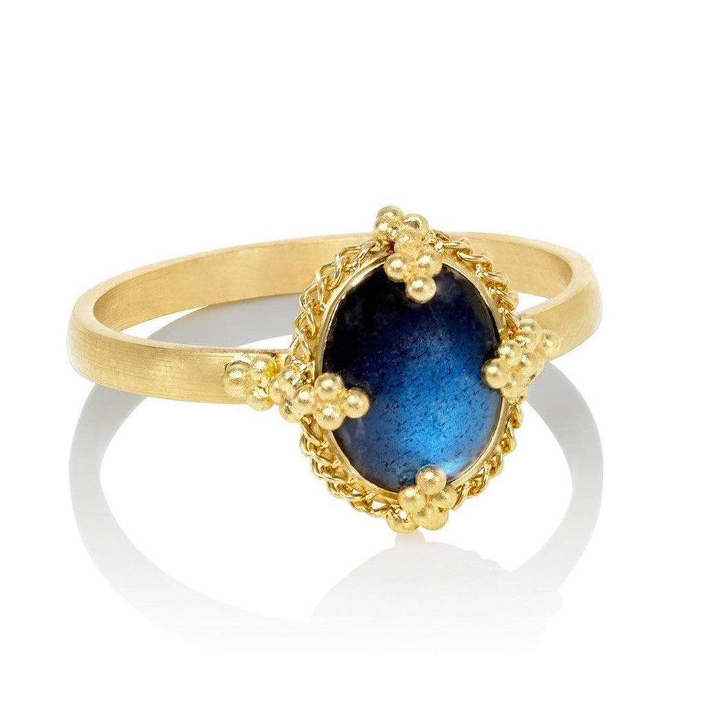 Oval Prong Moonstone ring with a deep blue gemstone, gold band, and intricate detailing.
