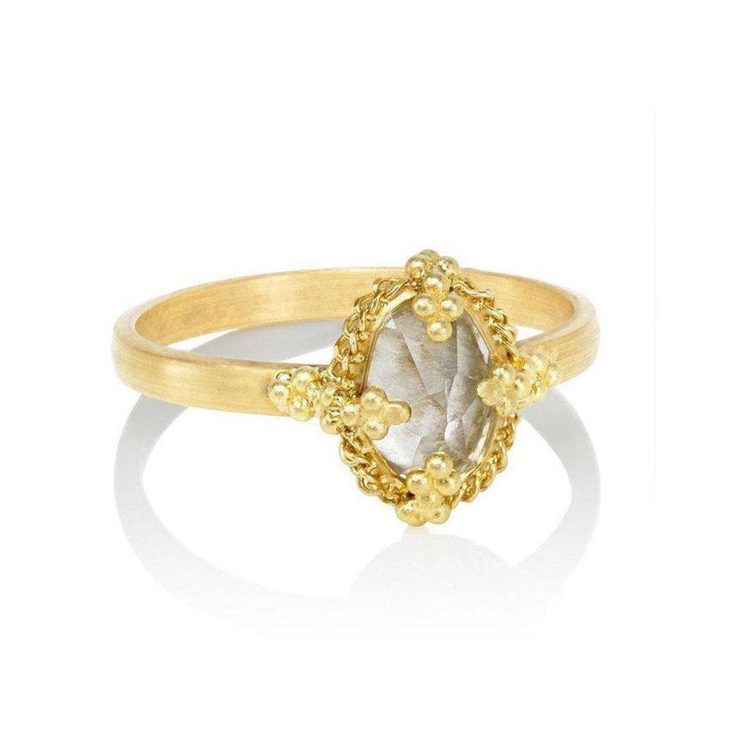 Oval prong white topaz ring in gold setting with textured detail.
