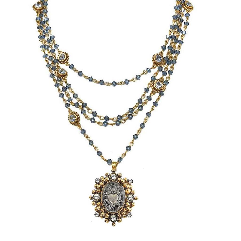 Layered gold necklace with blue beads and ornate silver pendant featuring a heart motif.

